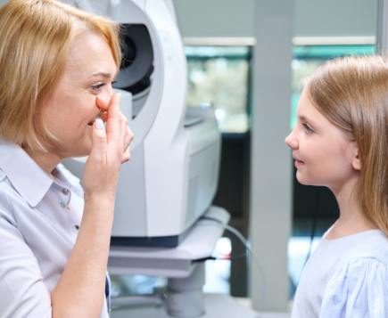 Profesional de la visión y niña junto a un equipo de examen ocular